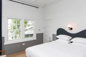 波特西Portsea Hotel的卧室配有白色的床和2扇窗户。