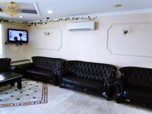 马斯喀特广场酒店的一间设有黑色真皮沙发和电视的等候室