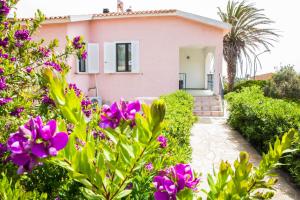 斯廷蒂诺Villa Diana affitta camere的粉红色的房子,前面有紫色的花