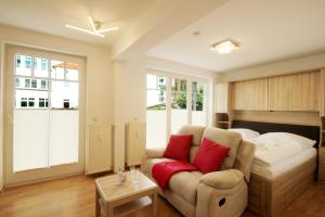 宾茨Haus Jahreszeiten by Rujana的一间卧室配有一张床和一张带红色枕头的沙发