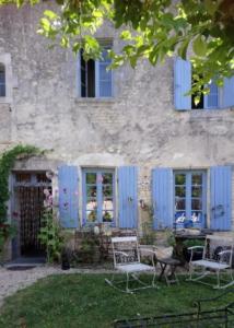 CresséLe vieux Prieuré的庭院里带蓝色百叶窗和椅子的房子