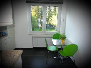 克莱沃Erdgeschosswohnung im Stadtzentrum的厨房配有桌子、绿色椅子和窗户