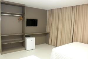 阿拉卡茹Transcar Suítes的一间卧室配有床、电视和书架