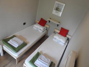 下厄尔什Lake Vendégház的小房间设有两张床,配有红色枕头