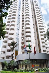 圣保罗Travel Inn Paulista Wall Street的前面有两面旗帜的高大的白色建筑