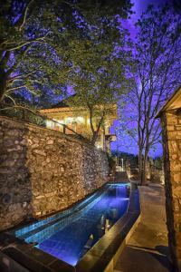 卡托劳塔翁Santa Marina Guesthouse的一座游泳池,在晚上靠近石墙