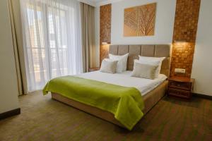 克拉斯诺达尔南梧桐酒店的一间卧室配有一张大床,上面有绿毯