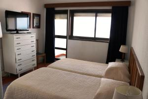 普拉亚德米拉马尔旅馆的一间卧室配有两张床和一个带电视的梳妆台。