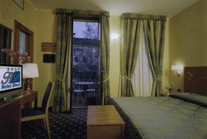 米兰迪耶奇酒店的酒店客房配有一张床、一张书桌和一台电视。