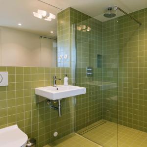 亨宁斯韦尔Trevarefabrikken的绿色瓷砖浴室设有水槽和淋浴