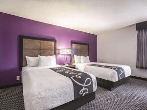 温莎洛克斯La Quinta by Wyndham Hartford Bradley Airport的紫色墙壁的酒店客房内的两张床
