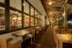 伊瓜苏马布瑟玛斯度假大酒店的餐厅设有木桌、椅子和窗户。