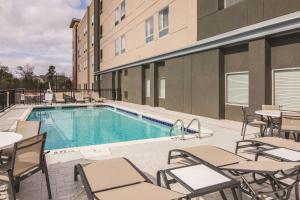 麦克多诺La Quinta Inn & Suites by Wyndham Atlanta South - McDonough的一座带桌椅的游泳池位于大楼旁
