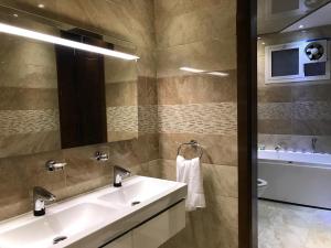 塔伊夫Deluxe Furnished Apartments的浴室配有盥洗盆、镜子和浴缸
