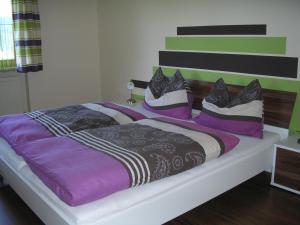 阿布特瑙豪斯奥贝拉斯拉克酒店的一间卧室配有一张大床,提供紫色和黑色枕头