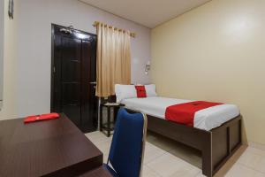 美娜多RedDoorz Plus near Pantai Malalayang Manado的一间卧室配有一张床、一张桌子和一张书桌