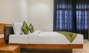 科泽科德Treebo Trend Casino的一张带白色床单和绿色枕头的床