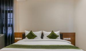 科泽科德Treebo Trend Casino的一间卧室配有一张带绿色和白色枕头的大床