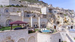 于尔居普卡帕多西亚卡亚卡匹高级洞穴酒店的一座大型石头建筑,在山丘上设有游泳池