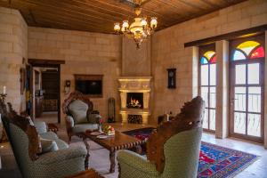 于尔居普卡帕多西亚卡亚卡匹高级洞穴酒店的客厅设有壁炉、椅子和吊灯。