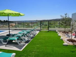 阿尔沃尔Villa Ria Alvor- Swimming pool & Jacuzzi的庭院设有椅子、遮阳伞和草地。