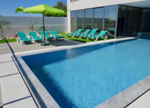 阿尔沃尔Villa Ria Alvor- Swimming pool & Jacuzzi的一个带椅子和遮阳伞的游泳池