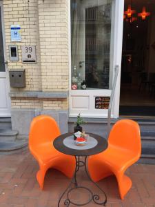 米德尔克尔克B&B Geste d' Alice的两张橙色椅子和一张黑色的桌子和椅子