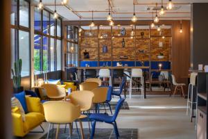 安特卫普安特卫普郁金香酒店的餐厅设有黄色和蓝色的椅子和桌子
