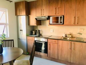 约翰内斯堡Kilkenny Cottages 2 bedroom unit的厨房配有木制橱柜、桌子和水槽。