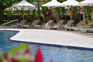 石垣岛ART 石垣岛酒店的游泳池旁的游泳池配有椅子和遮阳伞