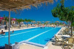 费拉圣托里尼岛露营/客房酒店的一个带桌椅和遮阳伞的游泳池