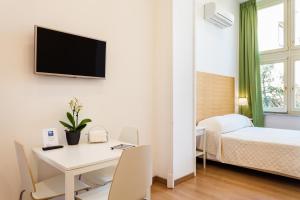 索伦托科索意大利套房酒店的一间设有一张桌子和一张床的房间和一间配有电视的房间
