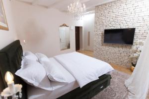 杜格普利耶San Mihael luxury rooms 1的一间卧室设有一张大床,砖墙上配有电视