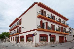 帕拉莫斯卡特琳娜公寓旅馆的白色的建筑,设有红色的窗户和阳台