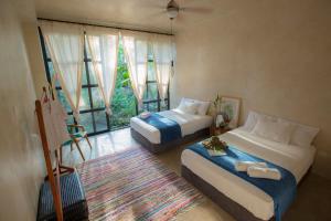 马尔多纳多港Kapievi Ecovillage的一间卧室设有两张床和大窗户