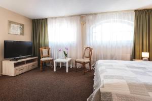 VitrupeHotel Karle的酒店客房配有一张床、两把椅子和一台电视