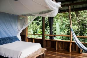 博卡斯德尔托罗La Loma Jungle Lodge and Chocolate Farm的一间卧室设有天蓬床和窗户。