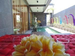 金巴兰巴厘岛金象精品别墅的一张桌子,上面有红色的椅子,在游泳池前有黄色的花朵