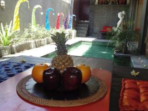 金巴兰巴厘岛金象精品别墅的池前桌子上的一盘水果