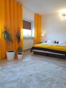 ÅšlesinZajazd WiK的一间卧室配有橙色窗帘,床上则种有植物