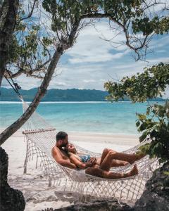 吉利特拉旺安彭杜克桑蒂酒店的两个人躺在海滩上的吊床上