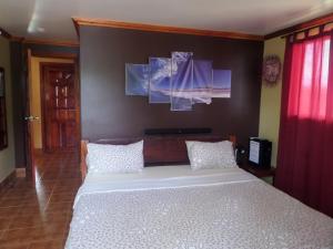 San IsidroSailfishbay Surf And Big Game Fishing Lodge的卧室配有一张白色床,墙上挂有两幅画作