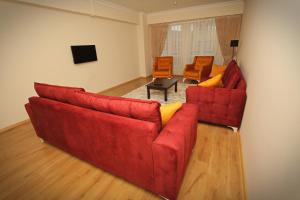 博卢özkanlar apart的客厅配有红色的沙发和两把椅子