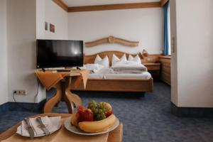 贝希特斯加登四季酒店的一间设有一张床和一张桌子及一盘水果的房间