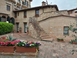 锡耶纳伊尔波佐迪圣安德烈亚住宿加早餐旅馆的一座石头建筑,前面有楼梯和鲜花