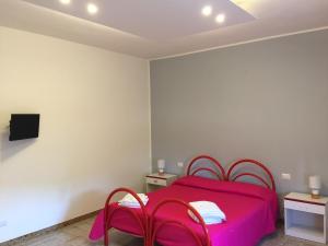圣卡特琳娜迪纳德Villa Benny a Due passi dal mare的一间卧室配有粉红色的床和两把椅子