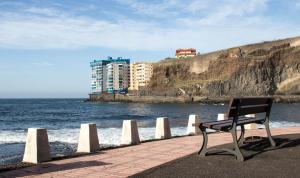 塔科龙特Acogedor apartamento con vista al mar的坐在海边砖砌走道上的长凳