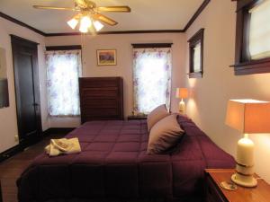 尼亚加拉瀑布Whirlpool Cottage的一间卧室配有紫色的床和吊扇