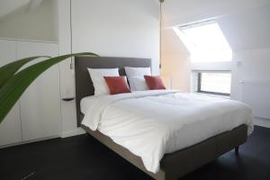 Beauvechainma-tinée的卧室配有带红色枕头的大型白色床