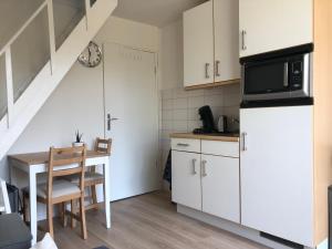 登堡Logies het Noordwestertje的厨房配有白色橱柜和带微波炉的桌子。